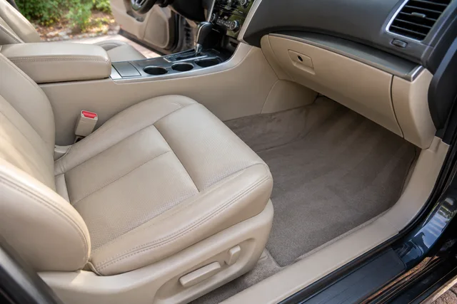 Tan leather seat and neatly cleaned carpet with visible natural texture